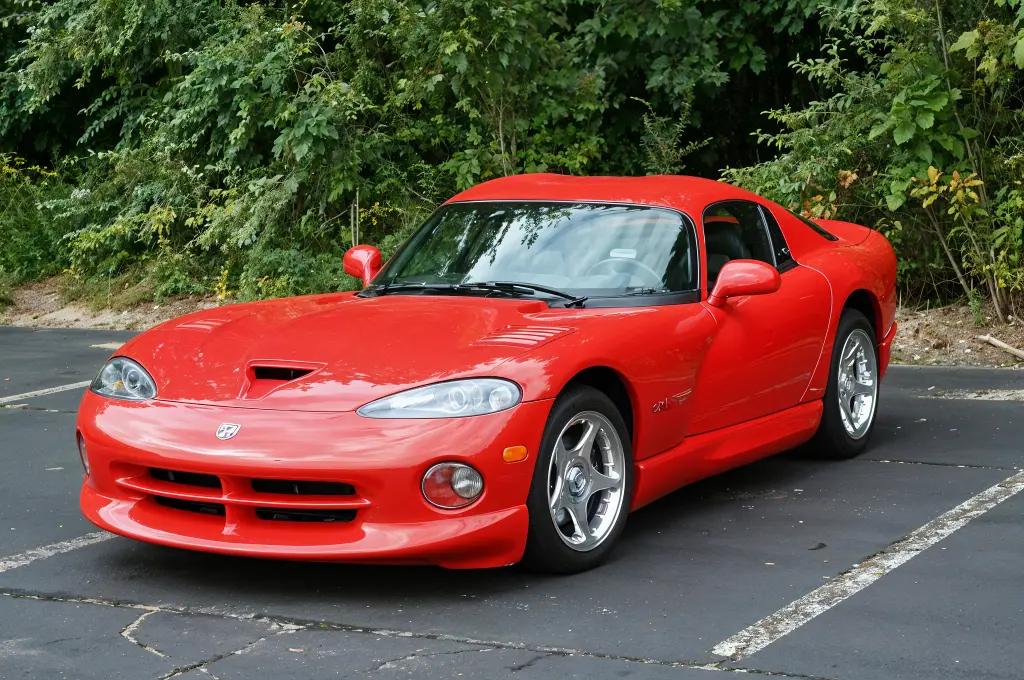 Dodge Viper GTS in red with white racing stripes, parked on a scenic road.