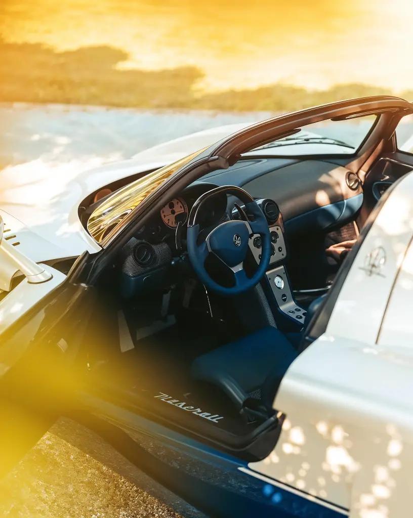 Interior shot of the Maserati MC12, showcasing its driver-focused cockpit with leather seats, carbon fiber, and branded racing harnesses
